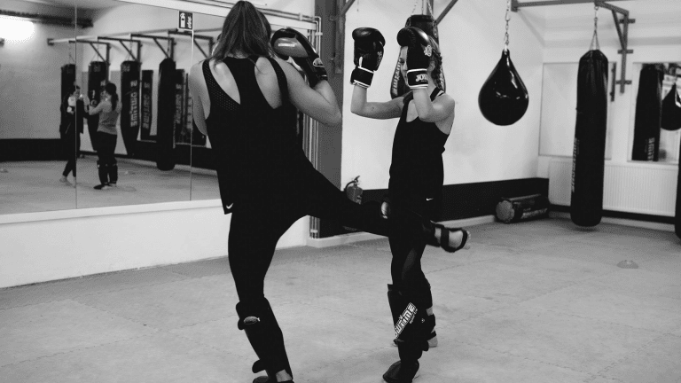 Zwei Frauen. welche gemeinsam Kickboxübungen ausführen.